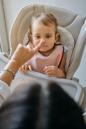Woman touching nose of little daughter at home