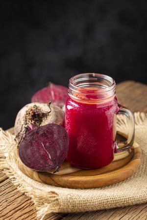 Red beet juice in a glass cup on the wooden table.