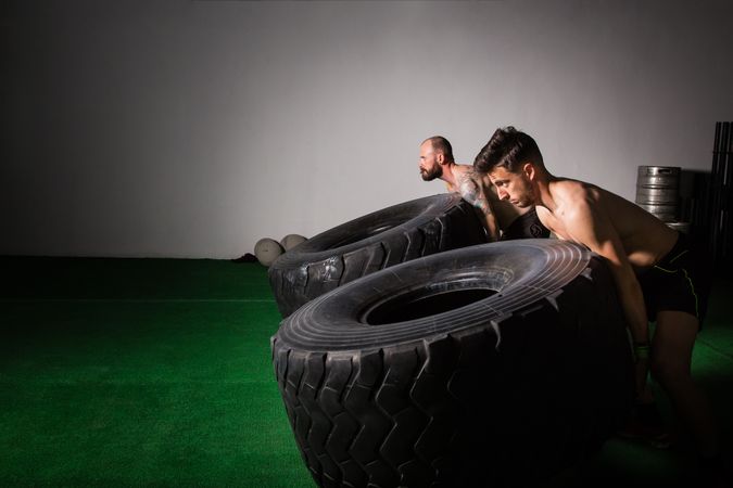Men flipping big tires in gym