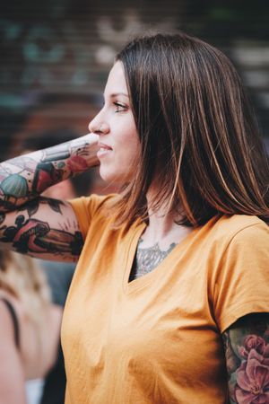 Cheerful tattooed woman smiling and standing on street