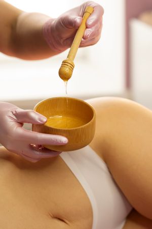 Gloved therapist lifts honey mixture with wooden dipper