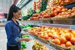 Woman choosing ripe tomatoes in supermarket