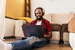 Black man in casual clothes using laptop at home.