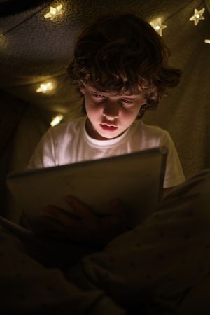 Calm boy drawing in dark blanker fort