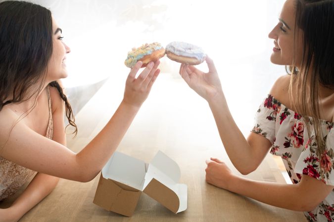 Happy women in sundresses with box of glazed desserts