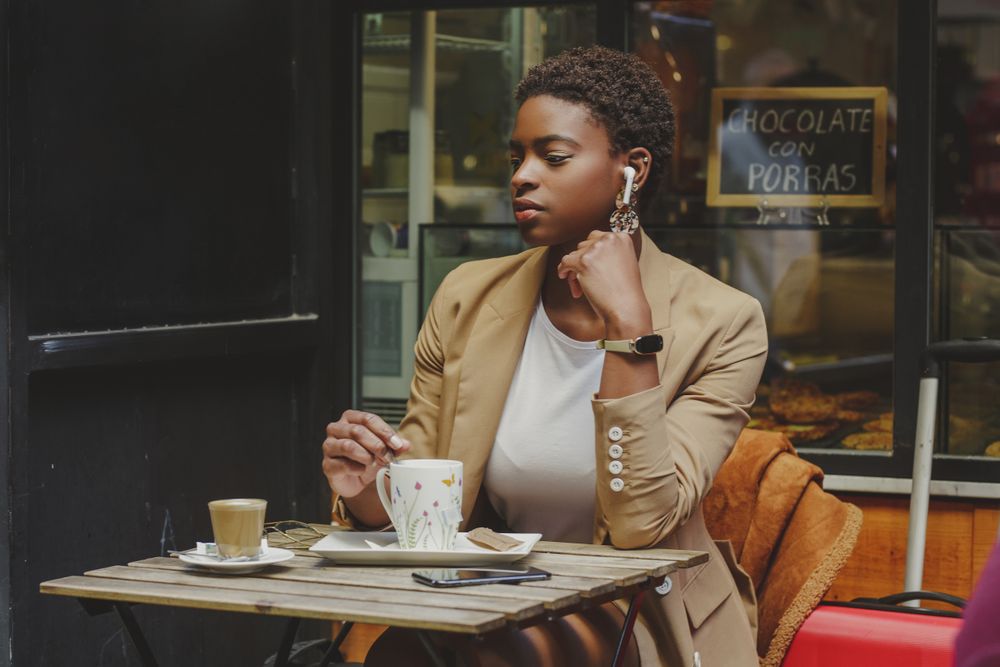 Black woman with cup of drink sitting at table in cafe