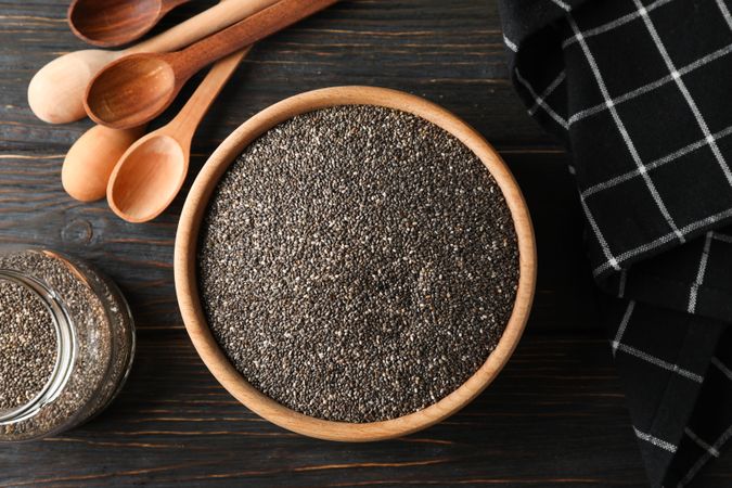 Chia in wooden bowl on wood background, top view