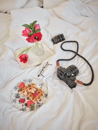 Waffles with photo camera and smartphone on bed