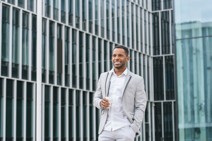 Black man with coffee standing in downtown
