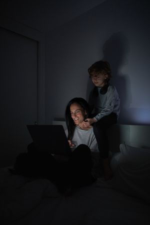 Mother and son surfing netbook in bedroom at night