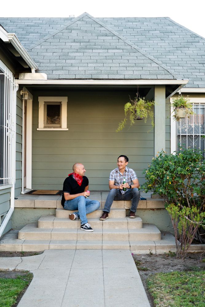 Male partners sitting on front porch in front of house enjoying an afternoon after work