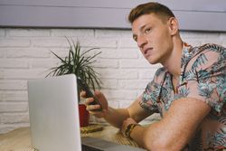 Man talking on smartphone while browsing laptop