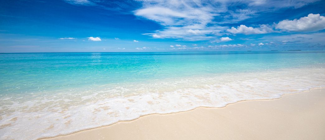Crystal clear water under a blue sky with clouds, wide