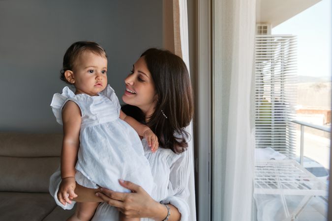 Loving mother looking at little daughter at home