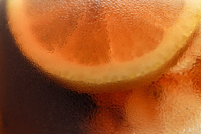 Side view background of cold cola with ice in glass, closeup