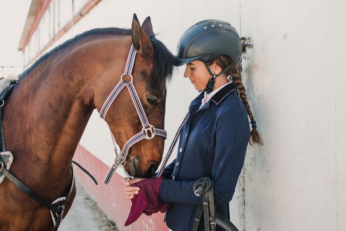 Woman in jockey outfit standing with horse
