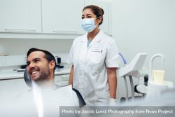 Dentist hygienist and patient looking at something and smiling bEKM15