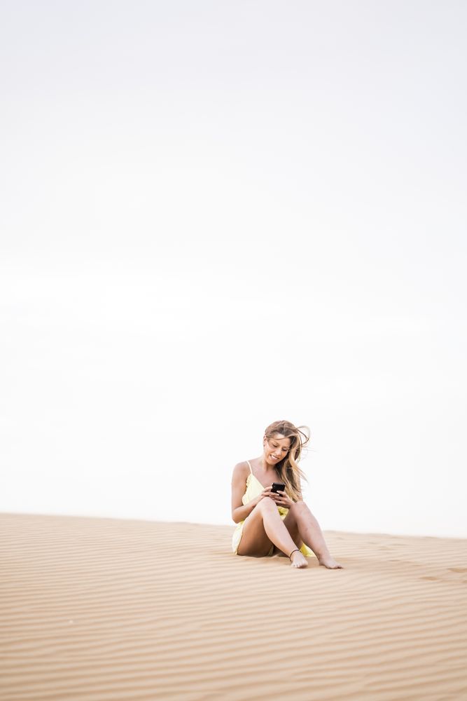 Thoughtful woman using smartphone in desert
