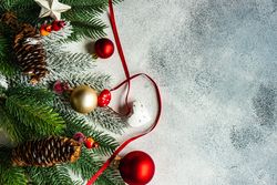 Christmas branch, pine cones, baubles and ribbon on grey background