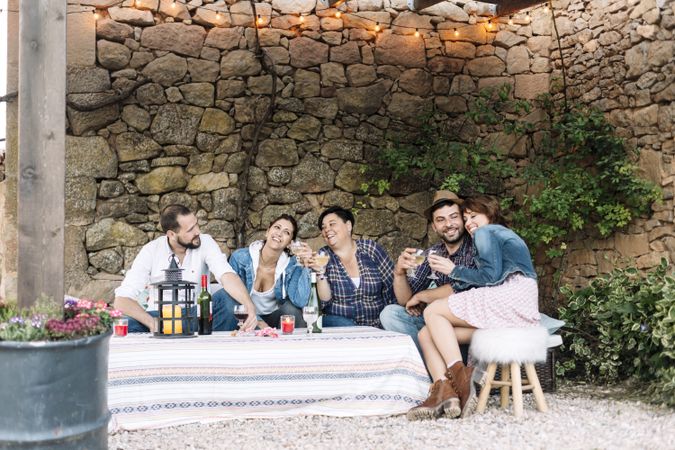 Group of happy friends sitting together while enjoying wine at a party