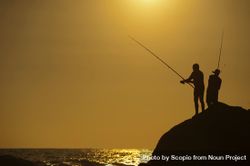 Silhouette of men fishing by shoreline at sunset bGQAv5