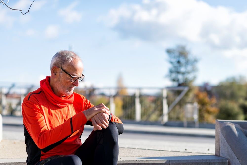 Older man sitting outside checking watch