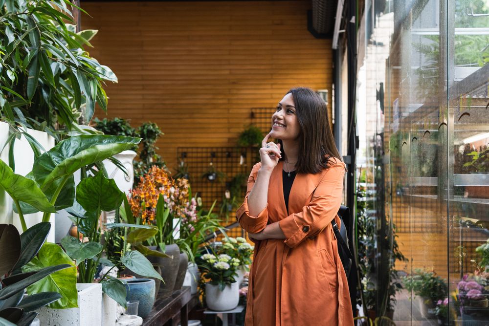 Cheerful woman choosing flowers in garden center
