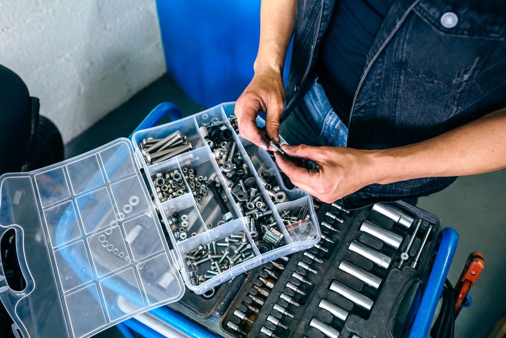 Mechanic's hands choosing screws from a tool box