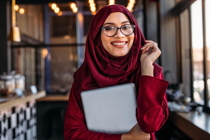 Muslim female holding a laptop while at a cafe