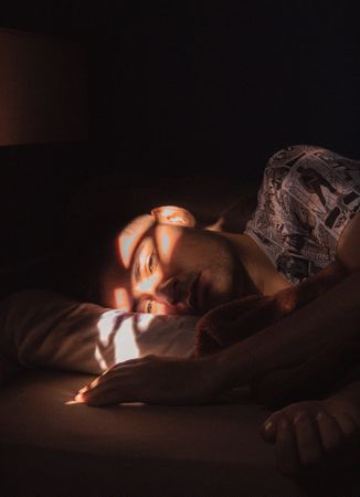 Man lying in bed resting with sun reflecting on his face