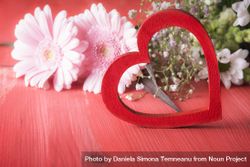 Decorative red heart and chrysanthemum flowers on red rustic table bDm7K0
