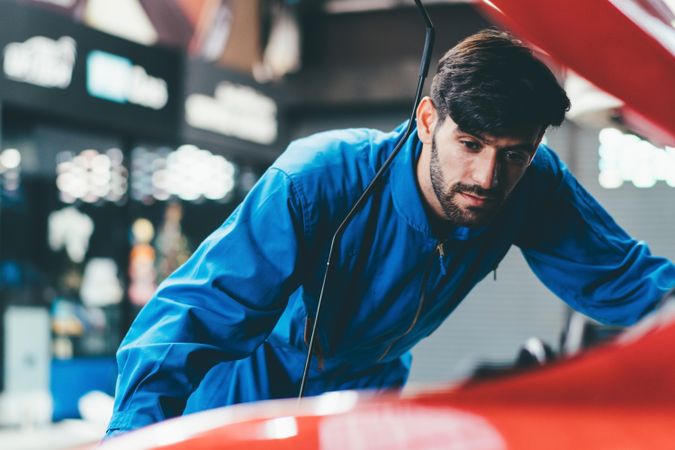 Male mechanic working on engine in vehicle