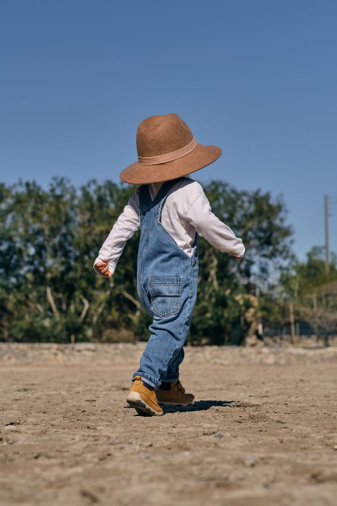 Anonymous little child strolling along paddock in ranch