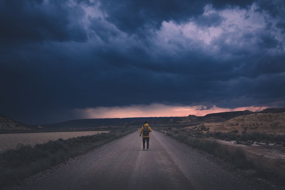 Man standing on road and looking at impressive evening sky
