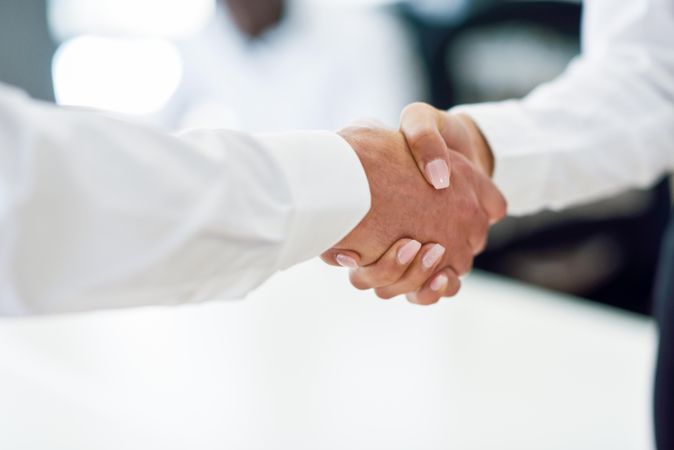 Close up of white male and female shaking hands in professional setting