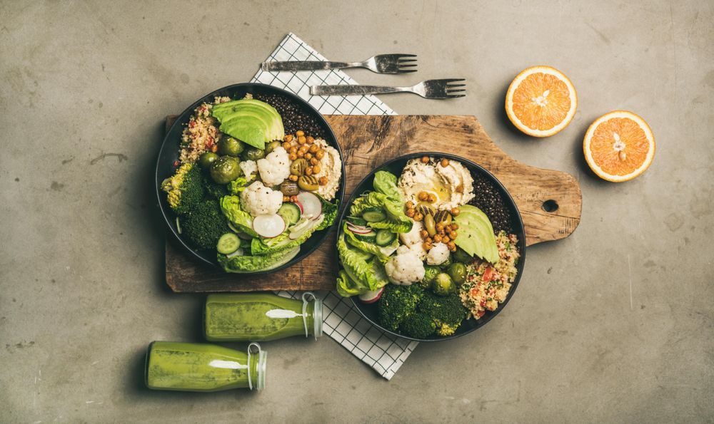 Two vegetarian bowls,  with smoothie, on placemat, bread board