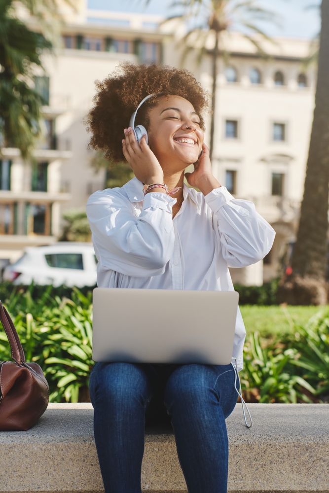 Black female freelancer working and listening to music on street