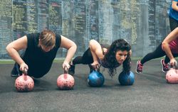 Sportswomen doing push-ups with kettlebells