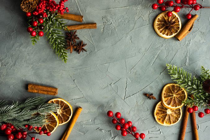 Christmas frame with fir tree, red berries, cones and decor on rustic concrete background with copy space