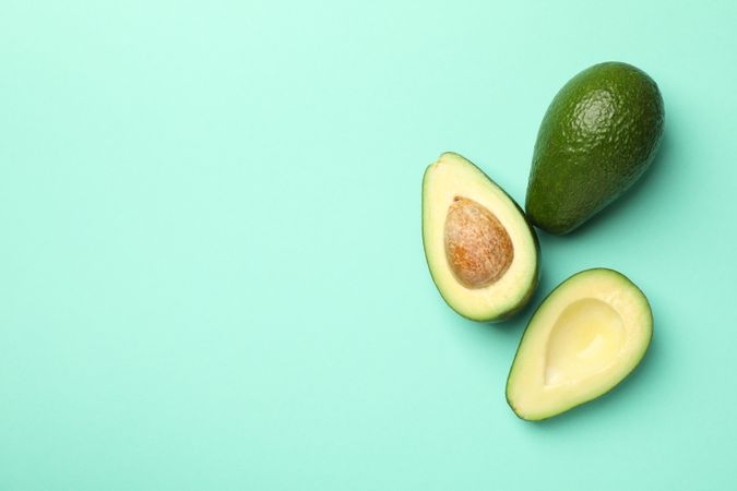 Ripe fresh avocado on mint background, top view