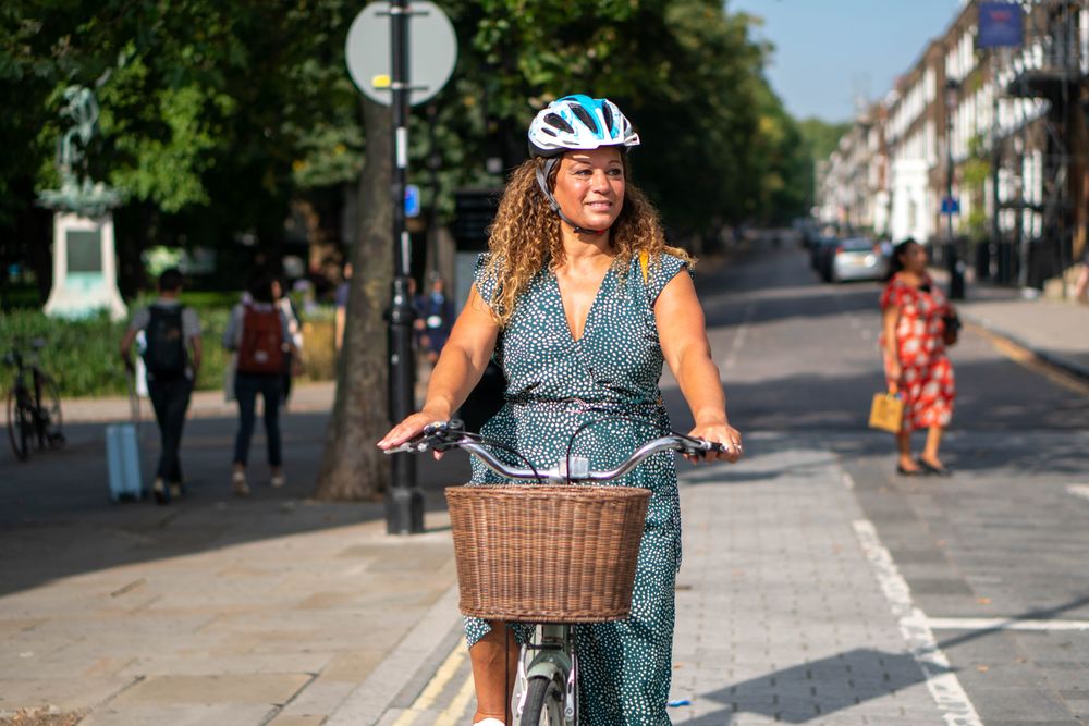 Happy Black woman standing tall while riding bicycle