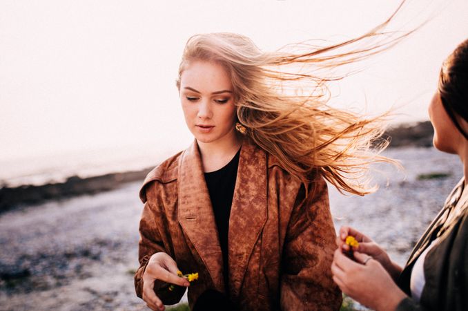 Young woman’s long hair blowing in the wind with her friend looking on