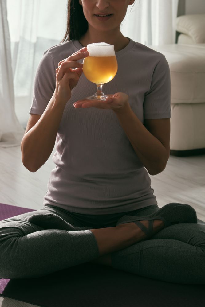 Anonymous woman with beer during yoga session