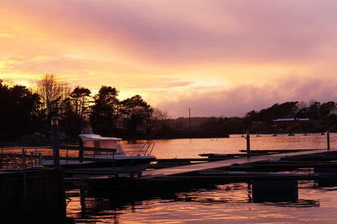 Boat by pier in twilight and distant forest silhouette