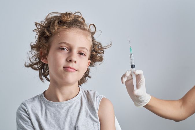 Calm kid with nurse showing syringe