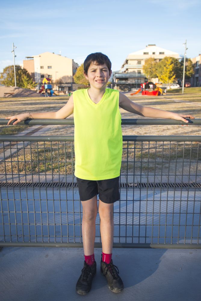 Half-length portrait of a smiling boy in a tank top smiling at the camera on a basketball court at sunset