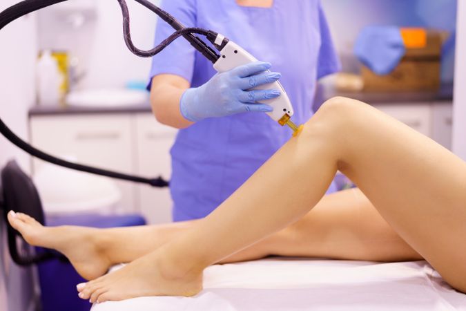 Client having laser hair removal at clinic on knee