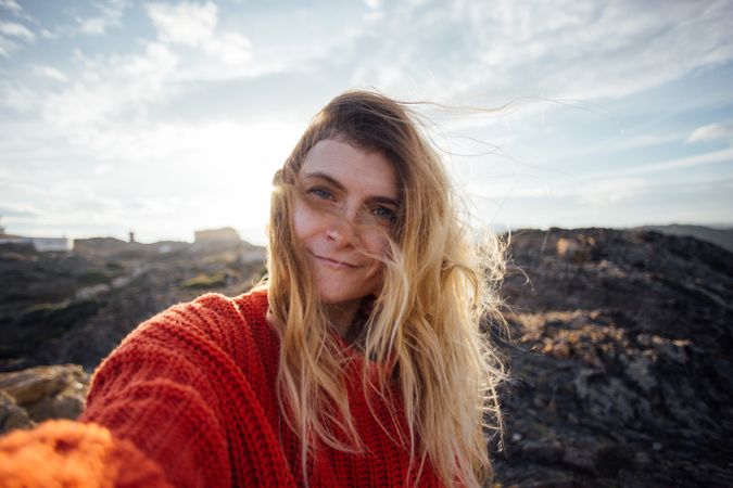 Woman in red sweater taking selfie on a hill