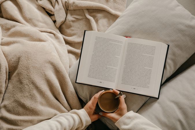Person reading a book on the bed