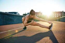 Fit woman stretching her legs on bridge before workout